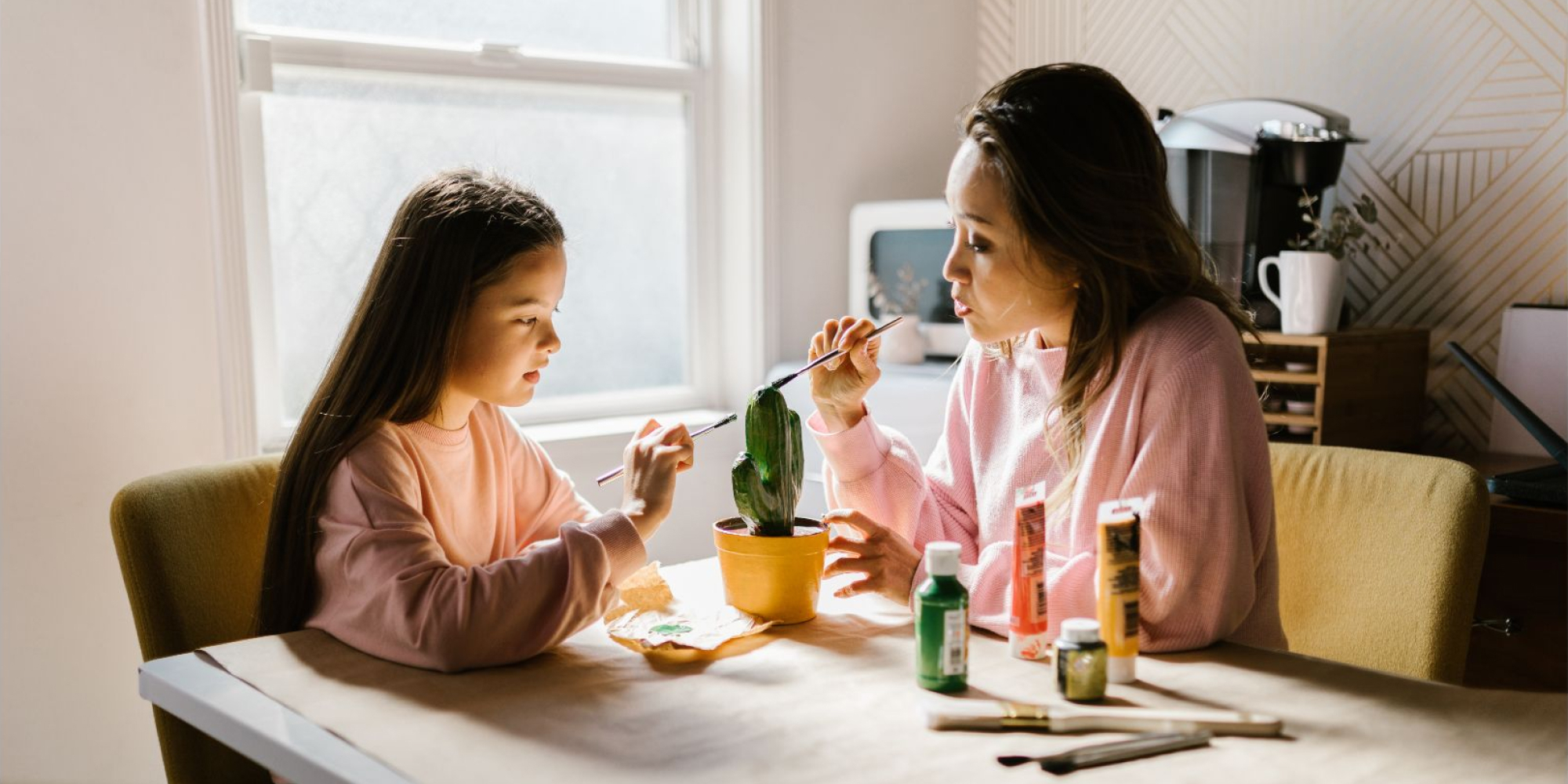 A mother and daughter painting a ceramic cactus.