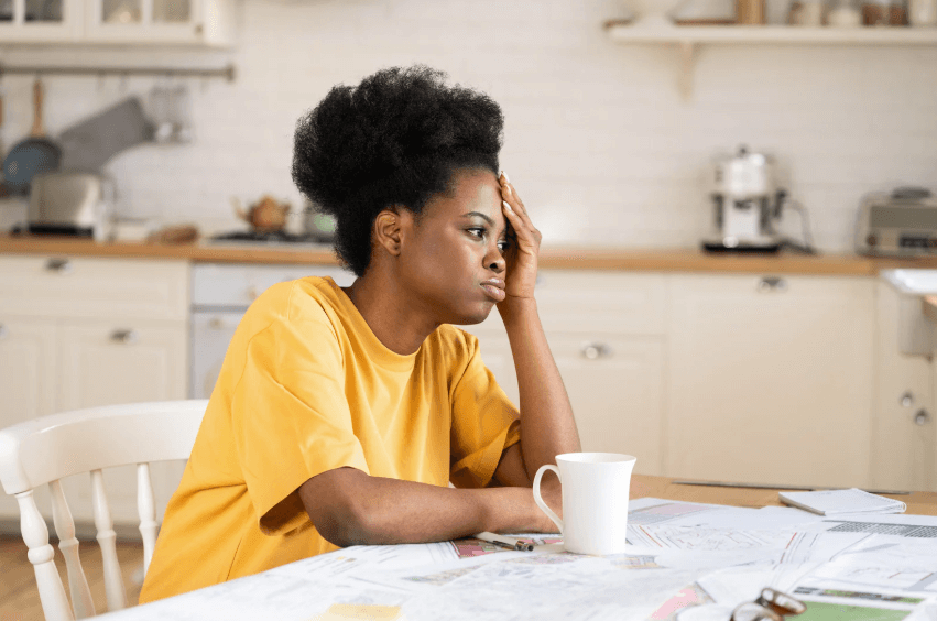 Tired woman working from home at table in kitchen.