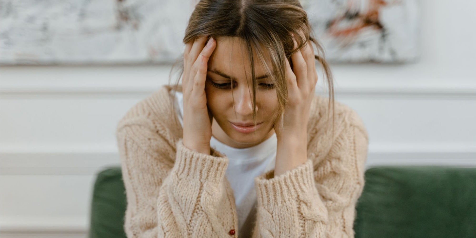 A woman who looks distressed holding her head in her hands.