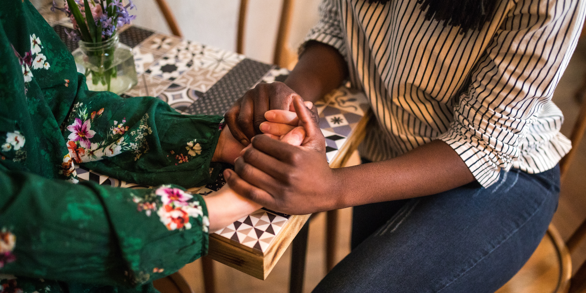 Two people holding hands across a colorful table.