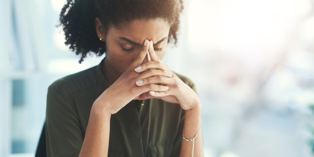 Woman with her hands folded and steepled against her face, looking meditative