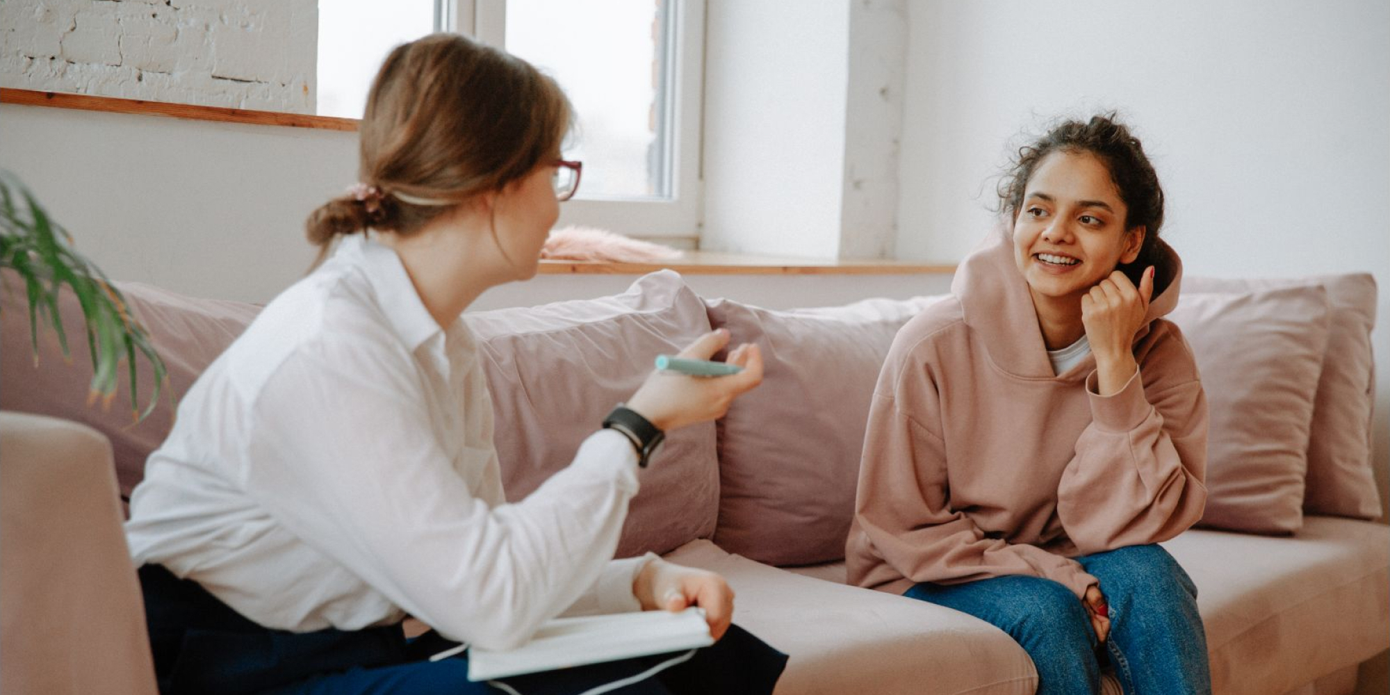 A young girl and her therapist begin therapy on a pink couch.