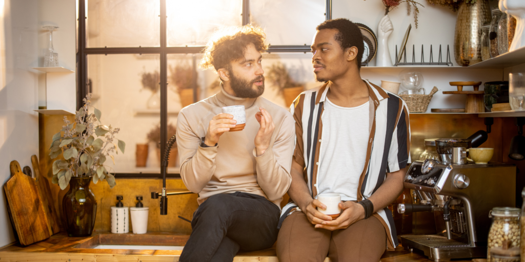 Two men sitting in their kitchen, communicating compassionately.