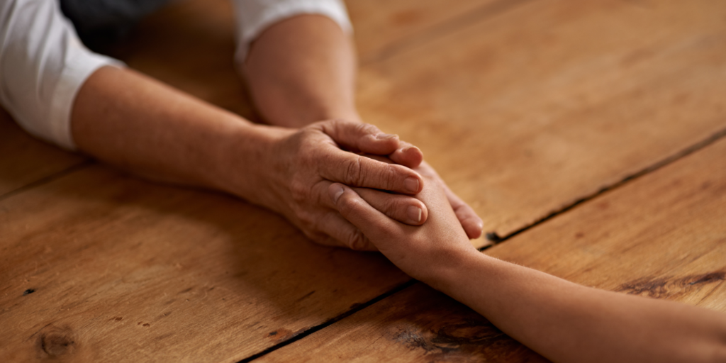 Two people holding hands across a table.