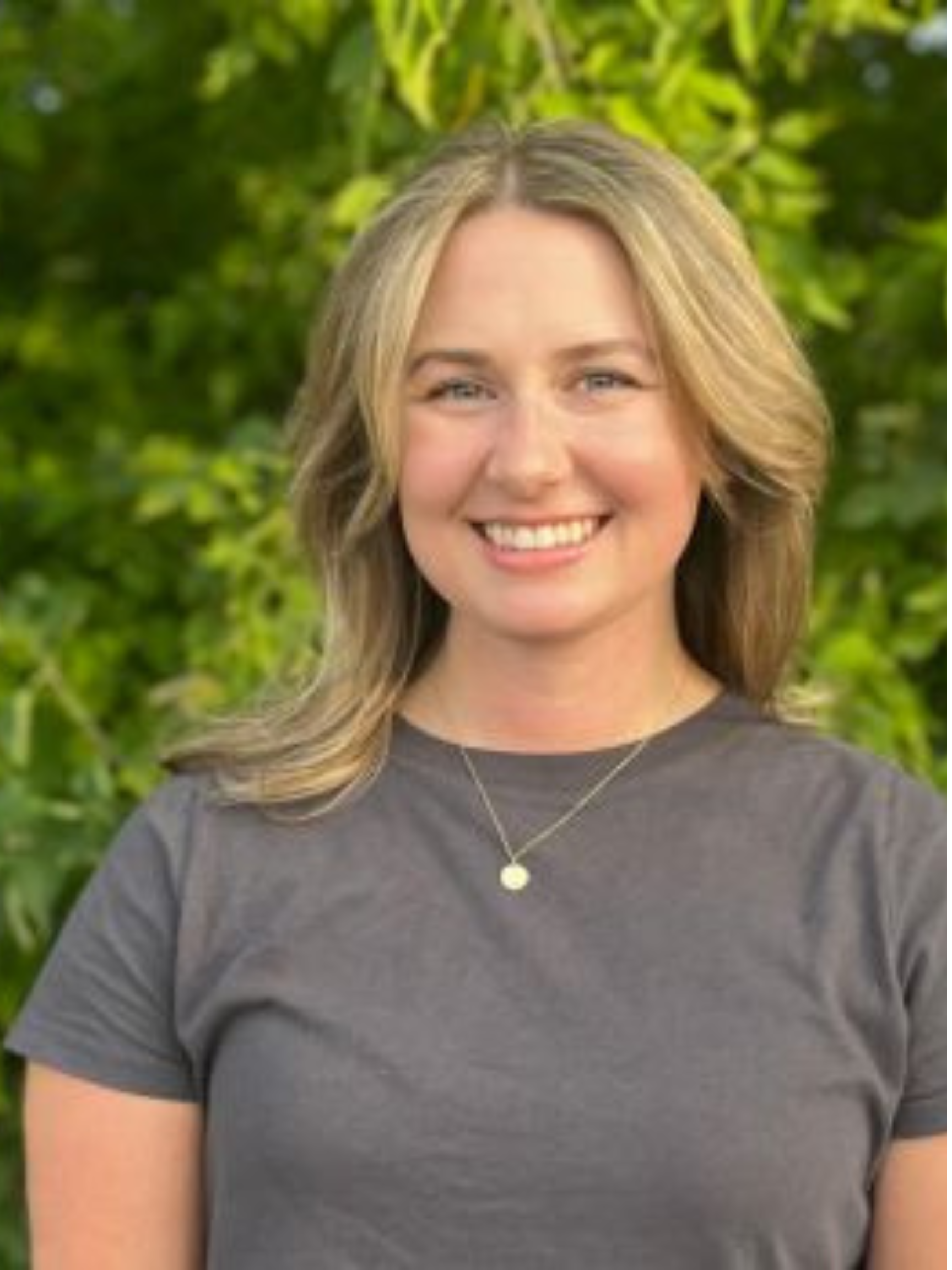 Samantha Rogers, LCSW wearing a black shirt against a leafy background.