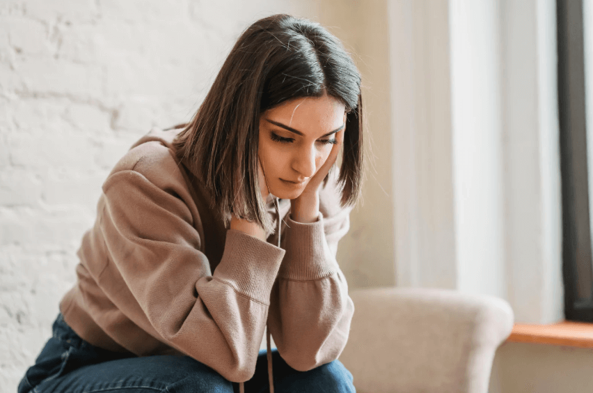 Woman sitting with her hands on her face.