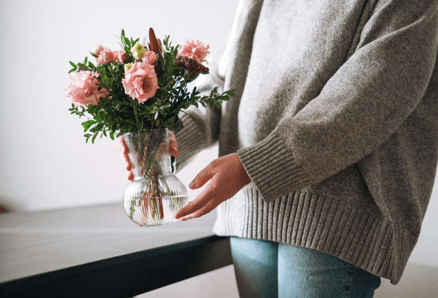 Woman holding bouquet of flowers in a vase.