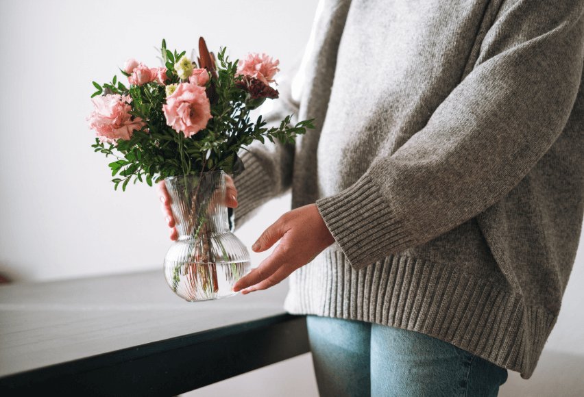 Woman holding bouquet of flowers in a vase.